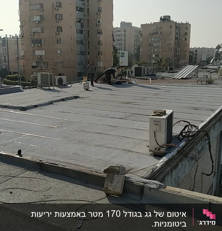 עובדים על גג עם יריעות איטום וכלי עבודה